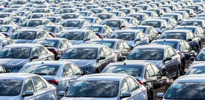 Dozens of cars parked in rows in an open-air parking lot.