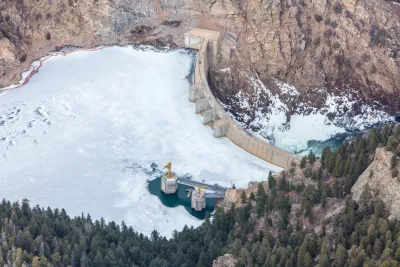 An aerial photo of Strontia Springs Reservoir. Most of the Reservoir is covered In ice. A stone wall blocks the water from flowing downstream.