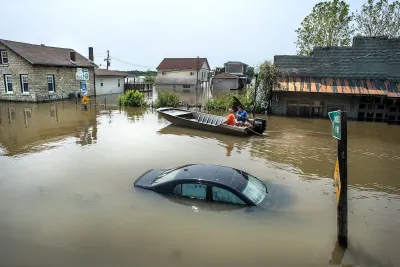 Submerged black car and people in small boat in flooded neighborhood in Grafton, Illinois.