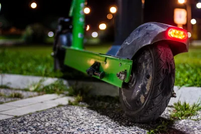 A green e-scooter at night with a red light on