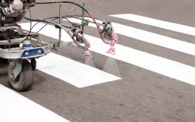 Machine spraying white crosswalk lines on street