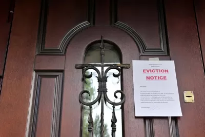 Eviction Notice taped to brown wooden door with black iron details