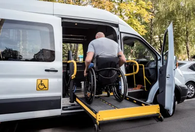 Man in wheelchair entering paratransit van on ramp.