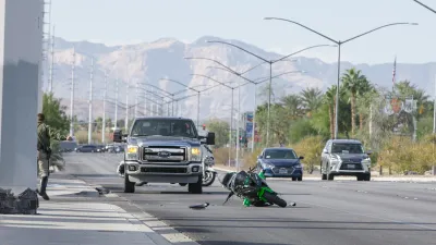 A green motorcycle lays crashed in a roadway with a large Ford pickup truck behind it in Las Vegas, Nevada.