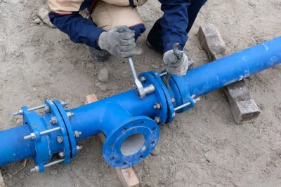 Worker working on exposed blue water pipe.