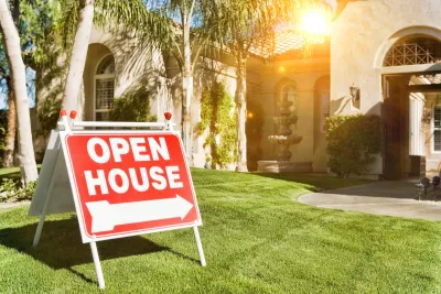 Red and white "Open House" sign on lawn in front of faux Spanish-style home with fountain in front.