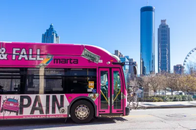 Pink MARTA public transit bus with Atlanta downtown skyline in background.