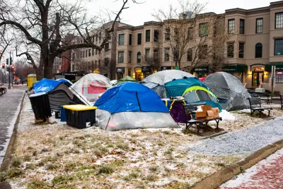 Group of tents and bins used by unhoused people in Washington, D.C. park with snow