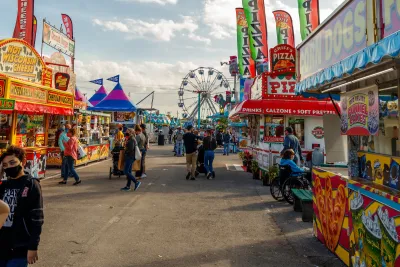 Amusement park boardwalk in Palm Beach, Florida with colorful booths and Ferris wheel.