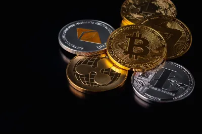 Loose, messy stack of silver and gold cryptocurrency coins with crypto logos.