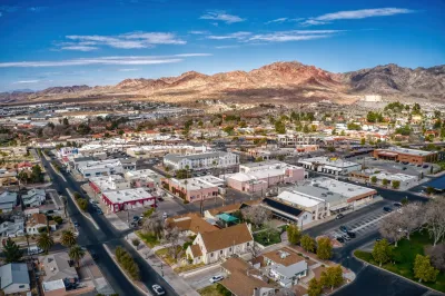 Aerial of small town in Nevada with mountains and bright blue sky in background.