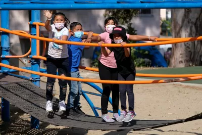 Children wearing COVID-19 masks on playground equipment