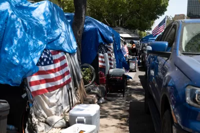 Line of tents with American flags draped on them on sidewalk in Los Angeles