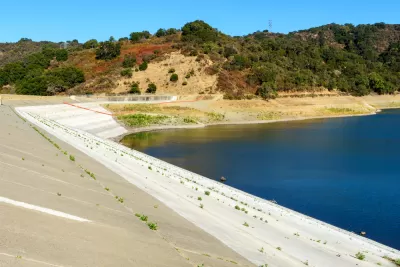 Concrete dam of almost dried, low water level Stevens Creek reservoir in San Francisco Bay Area, California.