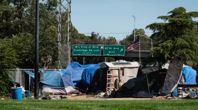 Encampment of unhoused people in Sacramento, California with freeway in the background