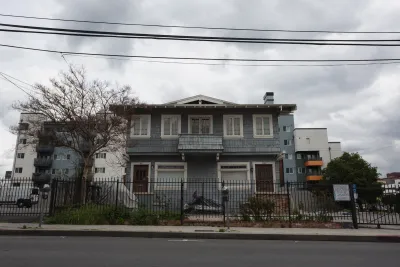 Grey two-story older home divided into two units inLos Angeles, California with modern apartment building visible in the background.