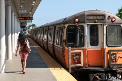 Orange Line train pulling into station with one woman waiting to board in Boston, Massachusetts