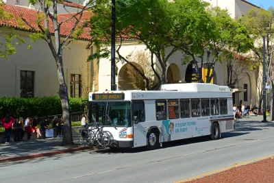 White San Jose city bus on street with Spanish-style architecture.