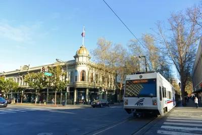 White VTA light rail train passing by historic building in downtown San Jose, California