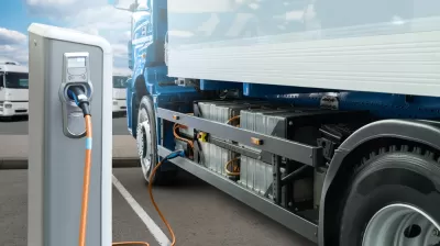 Concept rendering of white electric big rig truck plugged into charging station