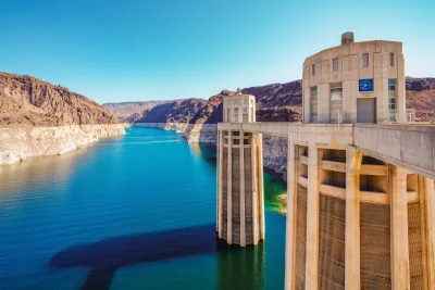 View from Hoover Dam of dam columns and Colorado River with water line visible above the water.