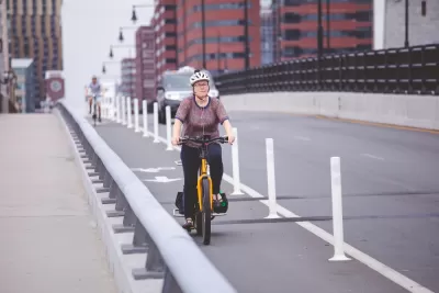 Woman on bicycle in protected bike lane on Boston bridge