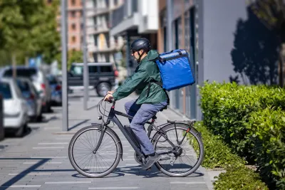 Man riding e-boike wearing large blue delivery backpack.