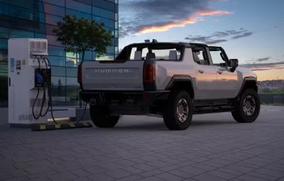 Rendering of grey convertible electric Hummer charging at a charging station against a sunset sky