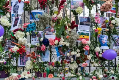 Close-up of fence covered with flowers, flyers, and other memorial items at site of deadly Twin Parks building fire