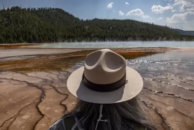 View of park ranger with tan hat from behind, ranger looking out at Grand Prismatic Spring in Yellowstone National Park, Wyoming