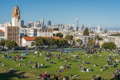 People sitting on large lawn in San Francisco city park.