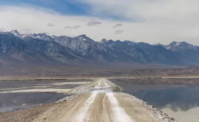 Unpaved road through Owens Lake bed with Sierra Nevada mountains in the background