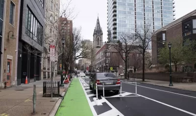 Green parking-protected bike lane in Philadelphia with old church in background