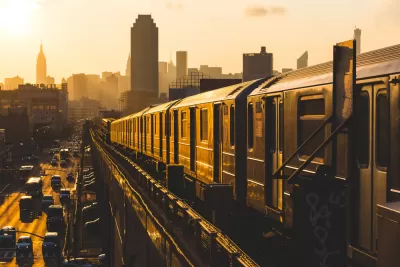 Golden sunset view of New York City subway train on elevated track with Empire State Building in background