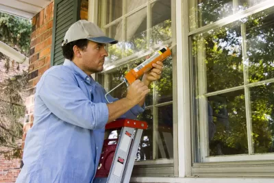 Worker caulking cracks in a home window