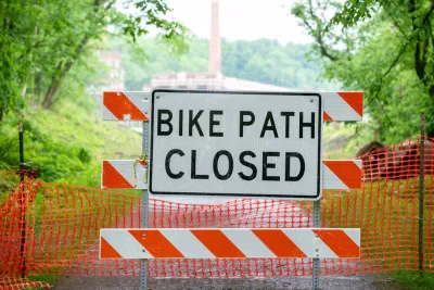 "Bike path closed" sign on orange and white construction barrier