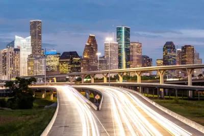 Dusk view of blurred car lights passing on freeway with Houston skyline in background