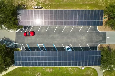 Overhead view of parking lot with solar panel canopies over parking spots and red car driving in
