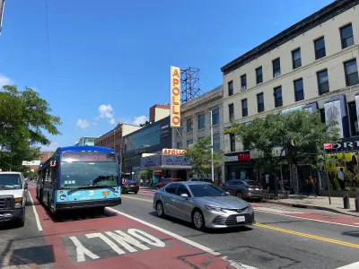 Red painted bus lane in New York City with marquee for Apollo theater in background.