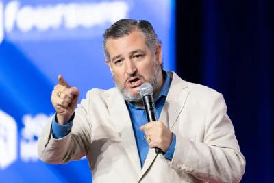 Senator Ted Cruz holding microphone speaking at an event on stage.