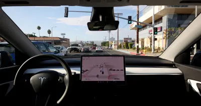 Interior dashboard of Tesla with large screen in middle.