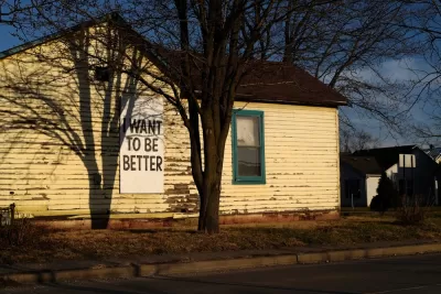 Single-story wooden home with weathered paint and "I want to be better" sign