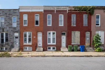 Vacant, boarded-up two-story urban homes in Baltimore, Maryland.