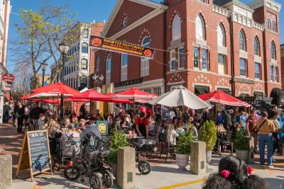 Busy street scene in Salem, Massachusetts with old brick church in background and red and white patio umbrellas.