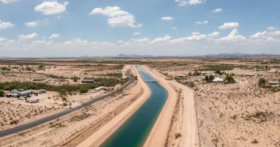 Aerial of Central Arizona Project aqueduct full of dark turquoise water surrounded by Arizona desert.
