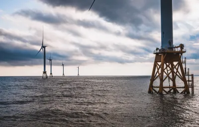 Offshore wind turbines on calm water with yellow scaffolding base.