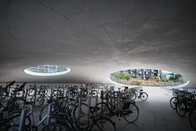 Partially underground concrete dome with circular openings and dozens of parked bicycles on University of Copenhagen campus.