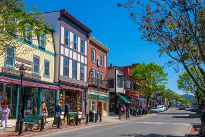 A lively town street with shops and people walking by colorful buildings