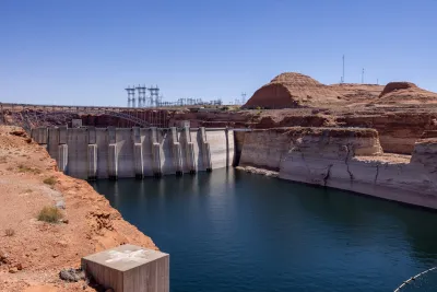 Lake Powell and dam surrounded by red rocks with visible 'bathtub rings' during drought.