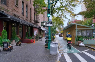 Green painted bike lane in New York City between sidewalk and outdoor dining kiosks